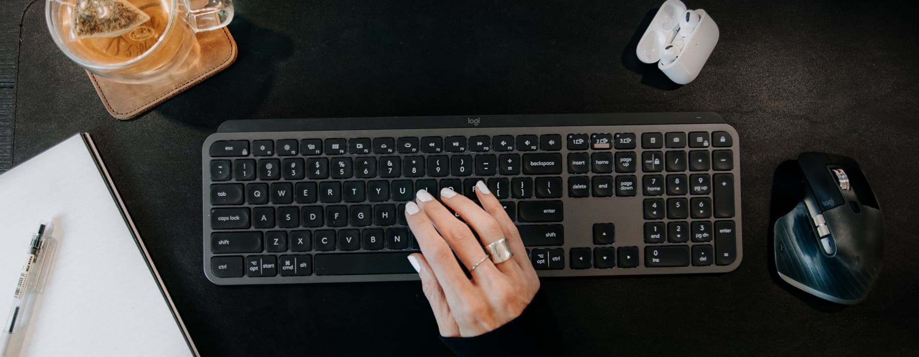 lifestyle image of a woman's hand typing on a black keyboard