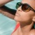 lifestyle image of a woman in a pool looking up toward the sun in sunglasses